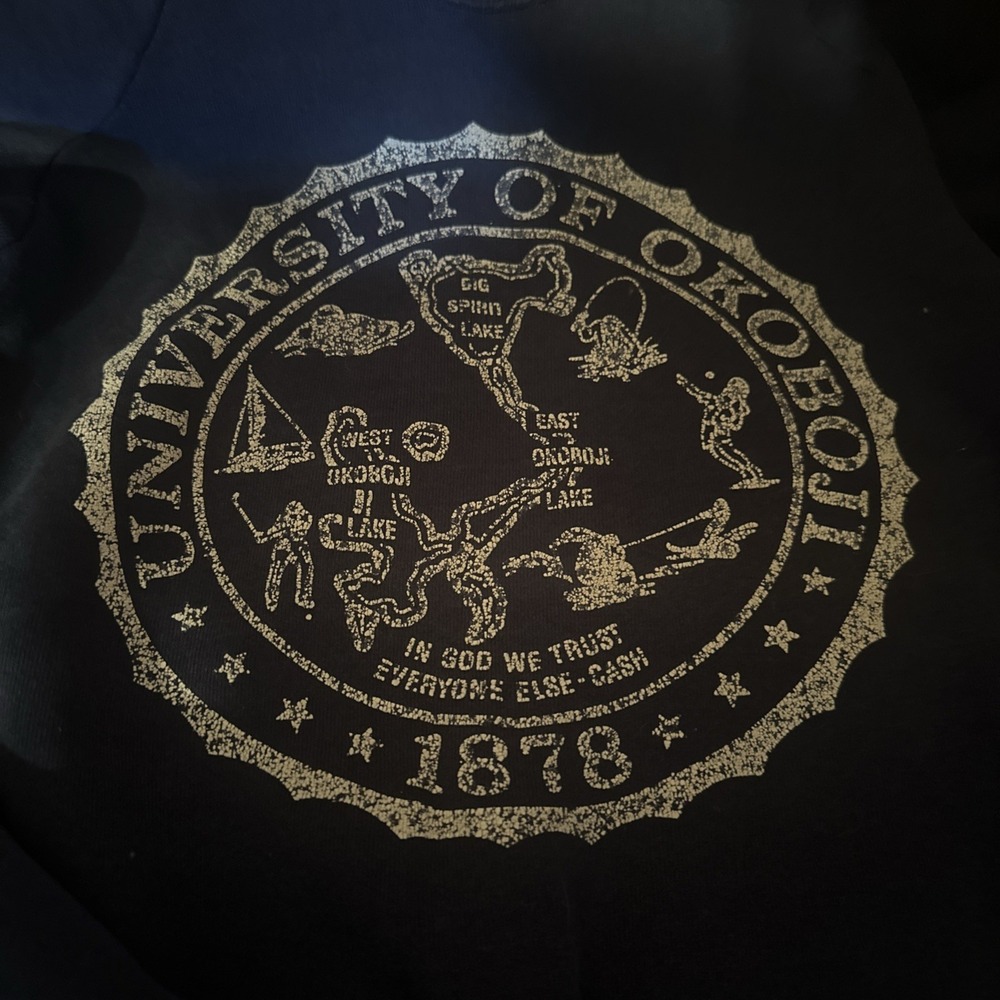 navy blue apparel features a vintage-style circular graphic Univ. Of Okoboji